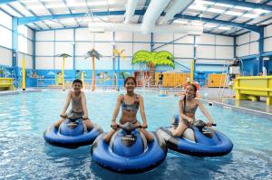 drei junge Mädchen reiten auf Schläuchen in einem Schwimmbad in der Unterkunft Skegness Retreats The meadows 13 Golden Palm Resort Chapel st leonards in Chapel Saint Leonards