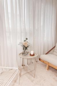 a white room with a table with a candle and flowers at Aurora Suite, Rovaniemi city center in Rovaniemi