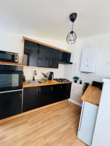 a kitchen with black cabinets and a wooden floor at Chantilly Spa Lodge near Parc Asterix in Montataire +13 photos