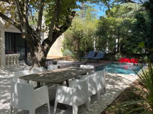 a table and chairs next to a tree and a pool at Villa 47 SUD in Villeneuve-lès-Avignon