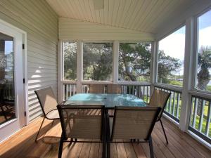 une véranda grillagée avec une table et des chaises dans l'établissement Dreamcatcher, à Edisto Island