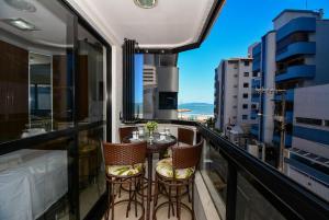 Un balcón con mesa y sillas y una vista en Aconchego em Itapema a 30 metros do Mar - ITA002, en Itapema
