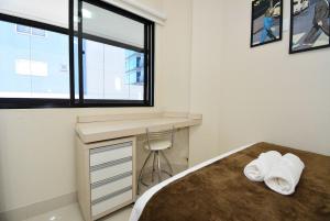 Un dormitorio con una cama y un escritorio y una ventana. en Aconchego em Itapema a 30 metros do Mar - ITA002, en Itapema 36 fotos más