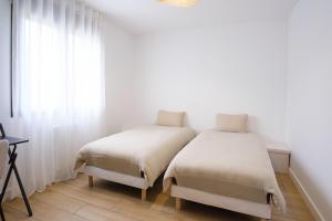 two beds in a room with white walls at Villa neuve 2025 - Calme & Confort, 8 pers, JURA 