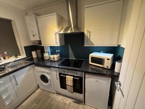 a kitchen with a stove top oven next to a microwave at Court Studio Apartment in Cardiff