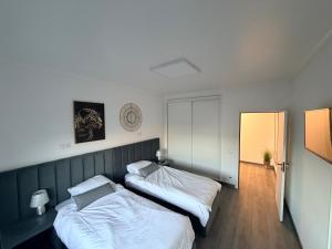 two beds in a small room with white sheets at Spacieux appartement à 200 m de la plage in Ovar