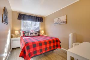 ein Schlafzimmer mit einem Bett mit einer karierten Decke und einem Fenster in der Unterkunft Big Bear Ski Hideaway! Cozy Cabin with Fenced Yard in Big Bear City Airport