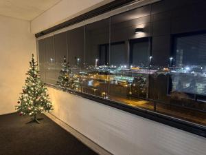 a christmas tree in front of a window with a city at Lapland Apartments with private sauna, wifi and parking next to the railway station in Rovaniemi +11 photos