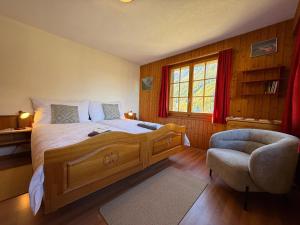 a bedroom with a large bed and a chair at Appartement Églantier in Evolène