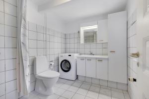 a white bathroom with a toilet and a washing machine at Annexgården 9A in Tommerup