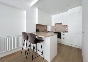 een keuken met witte kasten en een eiland met twee krukken bij Apartment Sunset Koksijde in Koksijde