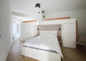 een wit bed in een witte kamer met een bedframe bij Apartment Sunset Koksijde in Koksijde