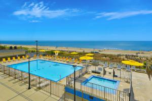 ein Swimmingpool mit gelben Sonnenschirmen und ein Strand in der Unterkunft Plaza 1404 in Ocean City