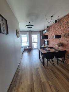 een woonkamer met een tafel en een bakstenen muur bij Apartamenty blisko dworca in Stargard