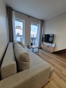 een woonkamer met een bank en een flatscreen-tv bij Apartamenty blisko dworca in Stargard