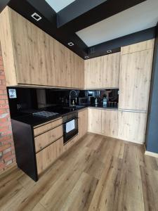 een grote keuken met houten kasten en zwarte apparaten bij Apartamenty blisko dworca in Stargard