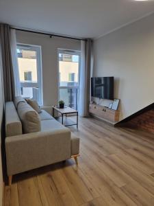 een woonkamer met een bank en een flatscreen-tv bij Apartamenty blisko dworca in Stargard