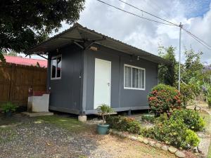 a gray house with a white door in a yard at Módulos Yunni in Uvita