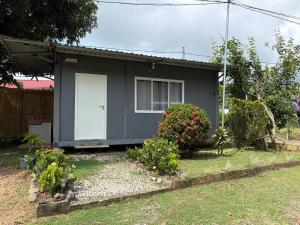 a gray house with a white door and some bushes at Módulos Yunni in Uvita +3 photos