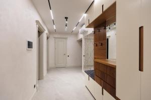 a hallway with a kitchen with white walls and wooden cabinets at Modern & stylish apartment in Chişinău