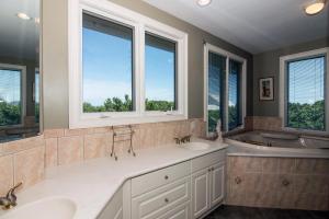 a bathroom with two sinks and a tub and two windows at Moonrise Point in Edisto Island +80 photos