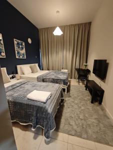 a hotel room with two beds and a television at TheGrid-Downtown HomeStay Abu Dhabi in Abu Dhabi +12 photos