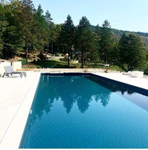 a swimming pool with blue water in a yard at Golf Forest Creek Villas in Zavidovići