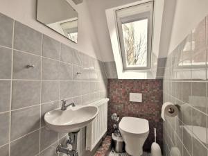 a bathroom with a sink and a toilet and a window at Wohnung 60 in Horumersiel