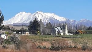 a snow covered mountain in the distance with a house in a field at The Holy Oaks in Duntroon +2 photos