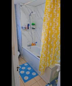 a bathroom with a tub and a yellow shower curtain at YouShelter in London