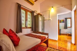a bedroom with a bed with red pillows at Anjuna House With Ocean View in Anjuna