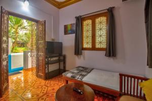 a bedroom with a bed and a table and a window at Anjuna House With Ocean View in Anjuna