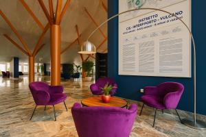 a lobby with purple chairs and a table at Holiday Inn Nola - Naples Vulcano Buono by IHG in Nola
