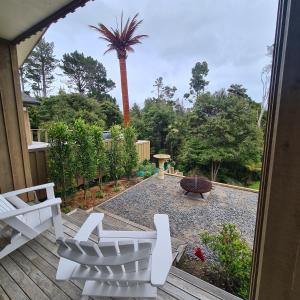 a patio with white chairs and a palm tree at Sandspit Hideaway in Sandspit +17 photos