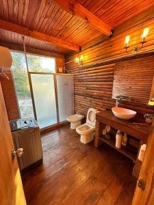 a wooden bathroom with two toilets and a sink at Macondo in Sauce de Portezuelo