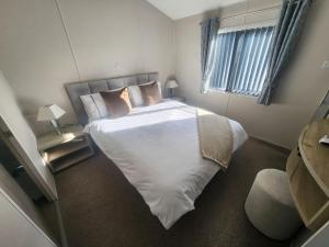 a bedroom with a large white bed and a window at Hot tub lodge grange leisure park Mablethorpe in Mablethorpe