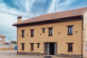 a large brick building with a red roof at La Casa Vieja de Robledo in Robledo de la Valdoncina