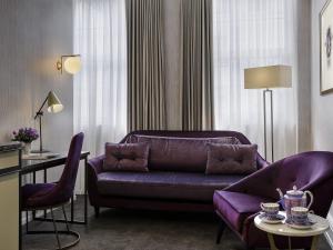 ein Wohnzimmer mit einem lila Sofa und einem Tisch in der Unterkunft Fable Auckland, MGallery in Auckland