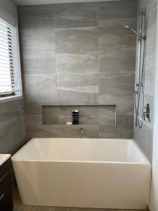 Una bañera blanca en un baño con ducha. en Tairua Views, en Tairua