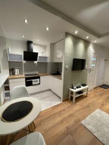 a kitchen with white cabinets and a table and chairs at Chill Apartament Gdynia in Gdynia