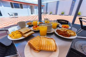 - une table avec des assiettes de produits pour le petit-déjeuner et du jus d'orange dans l'établissement Hotel Med Suites 94, à Barranquilla