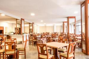 a restaurant with wooden tables and chairs and tablesktop at GoldMen Business Hotel Blumenau in Blumenau
