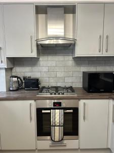 a kitchen with white cabinets and a stove top oven at Entire luxury home in Manchester in Bury +15 photos