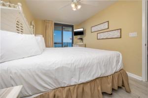 una camera da letto con un grande letto bianco con una finestra di Phoenix VI 6610 condo a Orange Beach