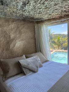 a bedroom with a bed with a view of the ocean at Rancho Navarro - Caverna in Pôrto de Pedras