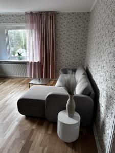 een woonkamer met een bank en een vaas op een tafel bij Cozy apartment in Åmål