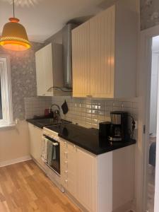 een keuken met witte kasten en een zwart aanrechtblad bij Cozy apartment in Åmål