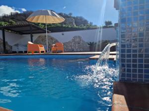 a swimming pool with a fountain and an umbrella at Casa Motta Camastra, panoramahouses, prive zwembad en prachtige vergezichten in Linguaglossa