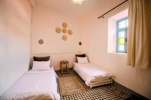 twee bedden in een kamer met een raam bij Dar janna in Essaouira
