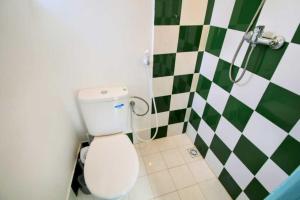 een badkamer met een toilet en een groene en witte geruite muur bij Dar janna in Essaouira +15 foto's